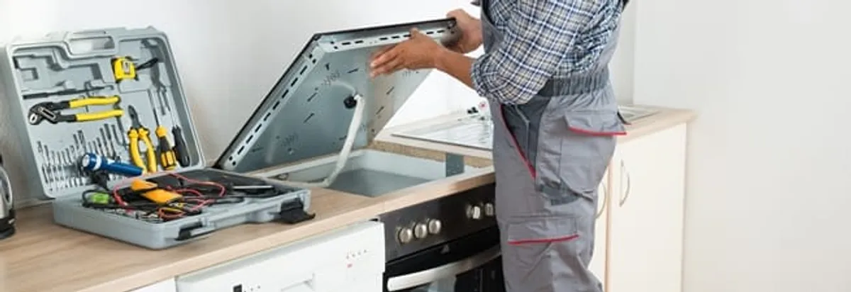 Cooktop repair technician lifting a built-in stovetop for service in Saint Petersburg, FL
